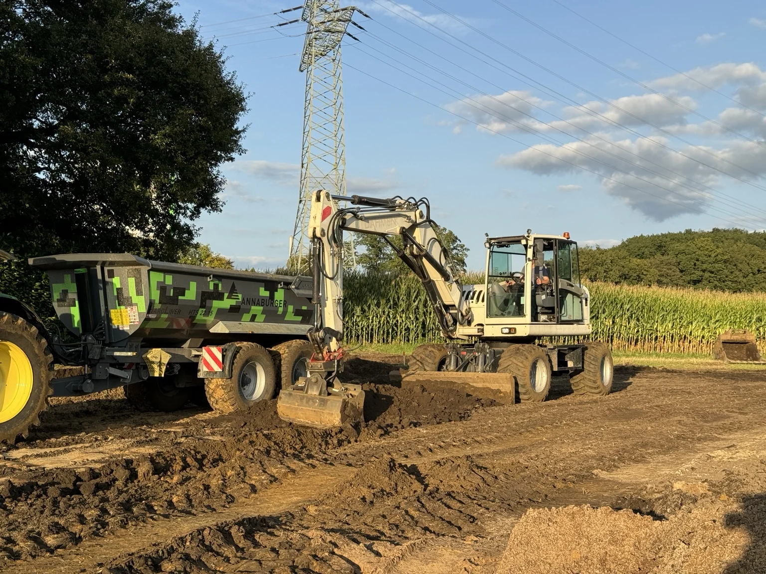 Mobilbagger und Traktor mit Muldenkipper bei Erdarbeiten